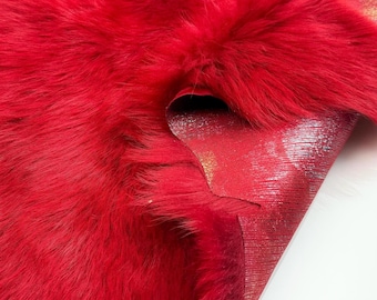 May include: Close-up of a vibrant red fur pelt. The fur is thick and plush, with a rich, saturated color. The underside of the pelt is visible, revealing a metallic, silver-toned backing. The texture suggests a luxurious material.