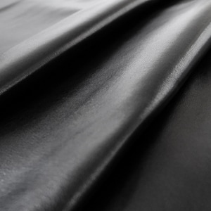 May include: Close-up of a smooth, black fabric with a soft, silky texture. The fabric is draped in folds, creating a luxurious and elegant look.