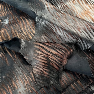 Peut inclure: Gros plan sur une peau de cuir à imprimé zèbre noir et marron. Le cuir a un motif texturé et gaufré et est plié en plusieurs couches.