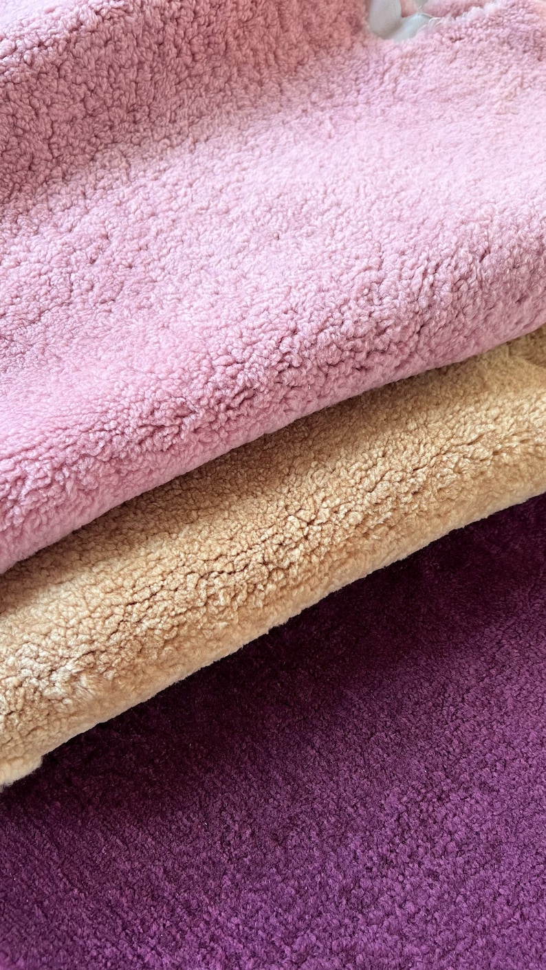 May include: Three fabric swatches in different colours: a light pink, a beige, and a deep purple. The fabric has a soft, fuzzy texture.