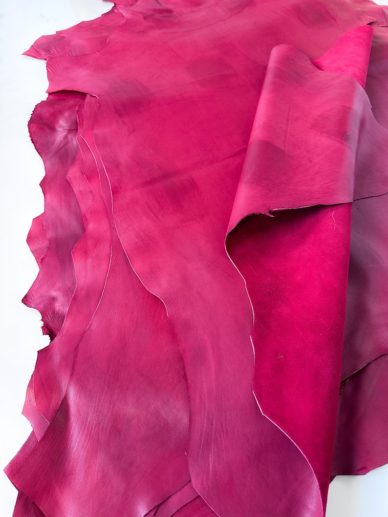 Pu&ograve; includere: Una pila di pelli di cuoio rosa. Il cuoio &egrave; morbido e flessibile, con una finitura liscia.