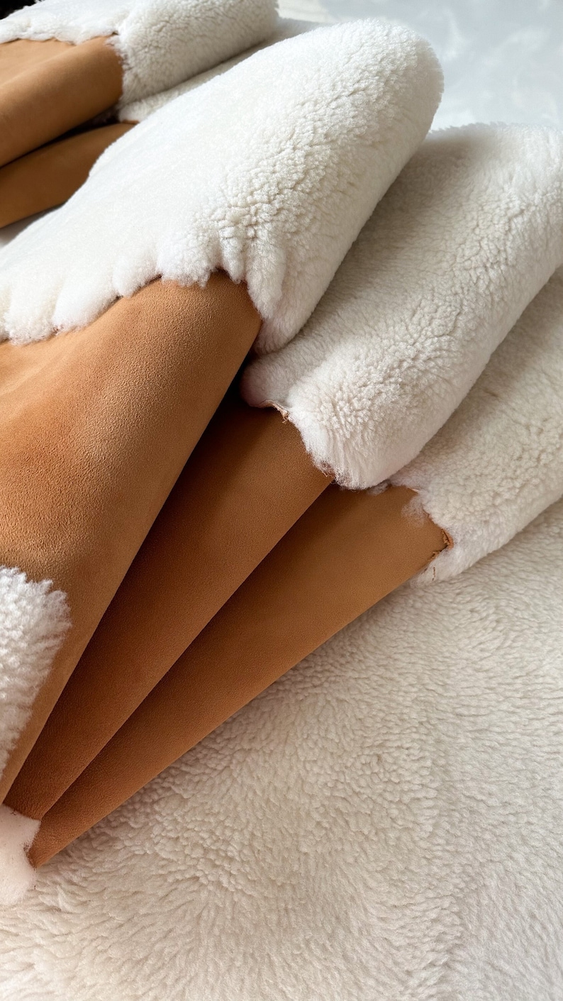 May include: A stack of brown suede and white faux fur fabric. The fabric is folded in a way that shows both sides of the material.