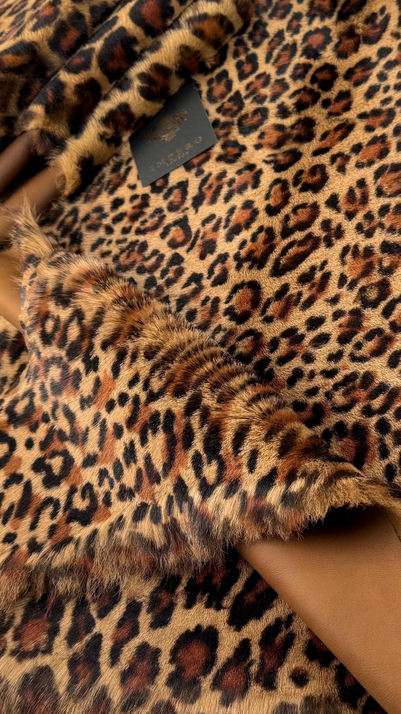May include: Close-up of a brown and black leopard print fabric with a black label that says "VENDOME LONDON" in gold lettering.