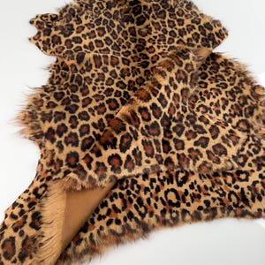 May include: A brown and black leopard print fur rug with a soft, fluffy texture.