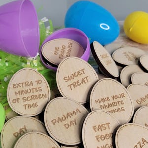 May include: Wooden Easter egg-shaped tokens with various family-friendly activities written on them, such as "Sweet Treat", "Pajama Day", "Fast Food Night", and "Scavenger Hunt".