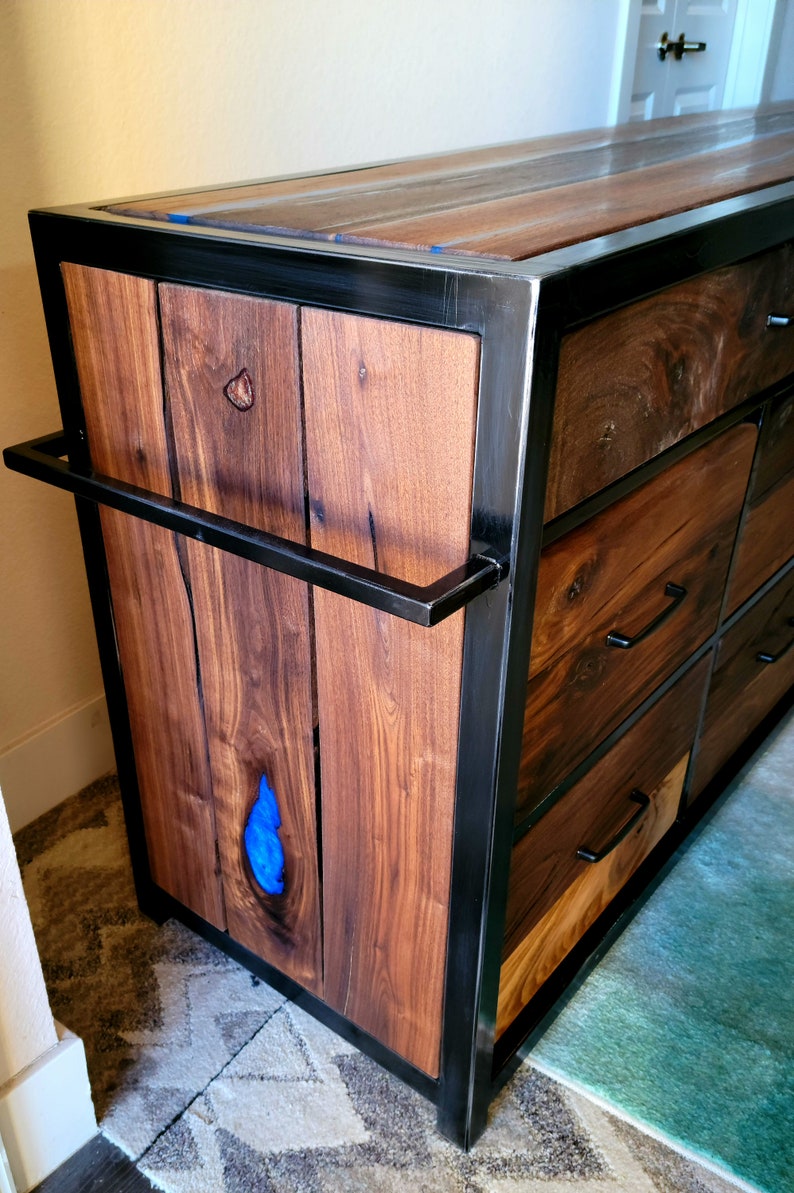 May include: A wooden dresser with a black metal frame and blue resin inlay. The dresser has multiple drawers with black metal handles.