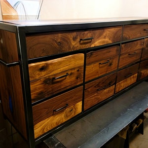 May include: A large dresser with a black metal frame and multiple drawers made of walnut wood. The drawers have black metal handles.