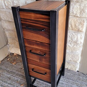 May include: A tall wooden dresser with four drawers and a black metal frame. The drawers have black metal handles.