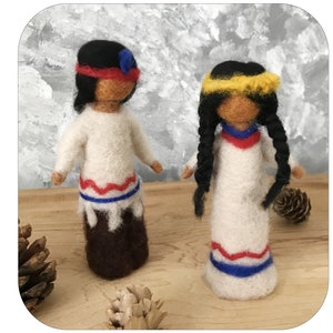 May include: Two handmade felt dolls, one with a red headband and the other with a yellow headband. Both dolls wear white tops and skirts with red and blue accents. The dolls have dark hair and are standing on a wooden surface.