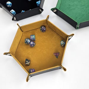 May include: A set of six-sided dice in a hexagonal, brown leather dice tray with a yellow felt interior. The dice are various colors with black numbers.