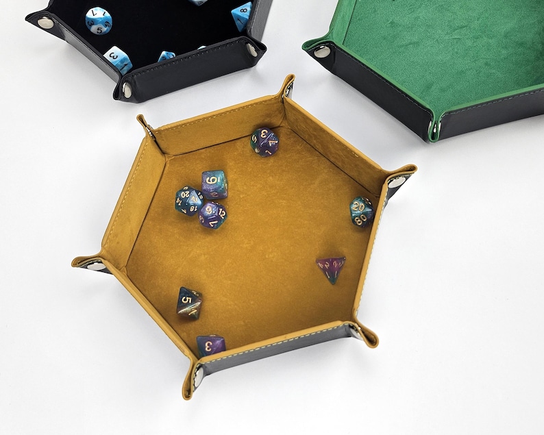 May include: A set of six-sided dice in a hexagonal, brown leather dice tray with a yellow felt interior. The dice are various colors with black numbers.