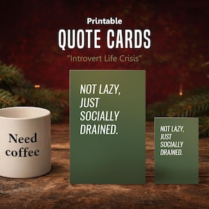 May include: A white ceramic mug with the words "Need coffee" and two green quote cards that read "Not lazy, just socially drained." The cards are in front of a Christmas tree.