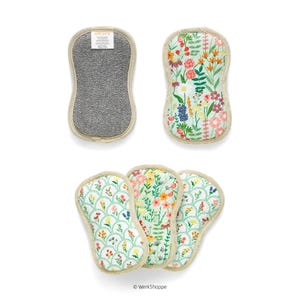 May include: A set of floral-patterned dish scrubbers. One scrubber has a gray, textured surface, while the others feature colorful floral designs on a white background. The scrubbers have a beige border.