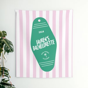 May include: A green motel key tag with white text that says "2024 Lauren's Bachelorette Palm Springs California" on a pink and white striped background.