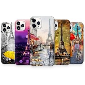Può includere: Cinque diverse custodie per telefono con immagini della Torre Eiffel a Parigi. Le custodie sono tutte trasparenti e mostrano diverse scene della Torre Eiffel, tra cui un'immagine in bianco e nero, un'immagine viola e rosa con luci, un'immagine colorata con una scena di strada, un'immagine di tramonto e un'immagine blu e bianca con una donna e un cane.