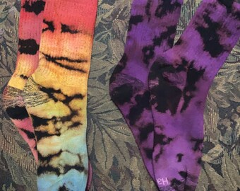 May include: Two pairs of tie-dye socks, one pair is purple and black, the other is rainbow colored.