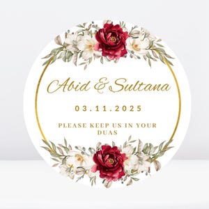 May include: A white circular sticker with a gold border and floral design. The text "Abid & Sultana" is written in gold script. The date "03.11.2025" is written below the names. The text "Please keep us in your Duas" is written below the date.