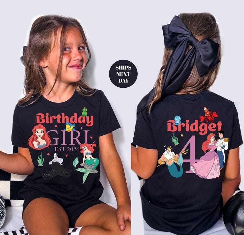 A young girl wearing a black t-shirt with a Disney character design and text, sitting against a white background.