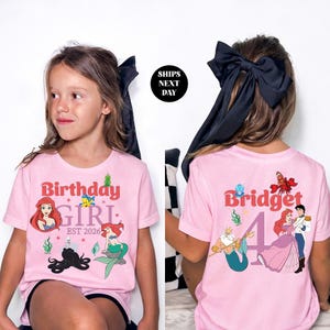 two young girls wearing pink t-shirts with the same design, including characters from the Disney movie "The Little Mermaid".