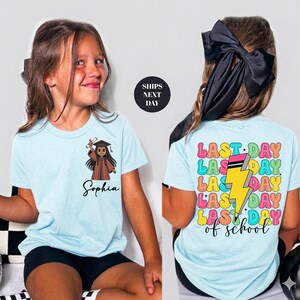 A young girl wearing a light blue t-shirt with a cartoon character and text printed on it.