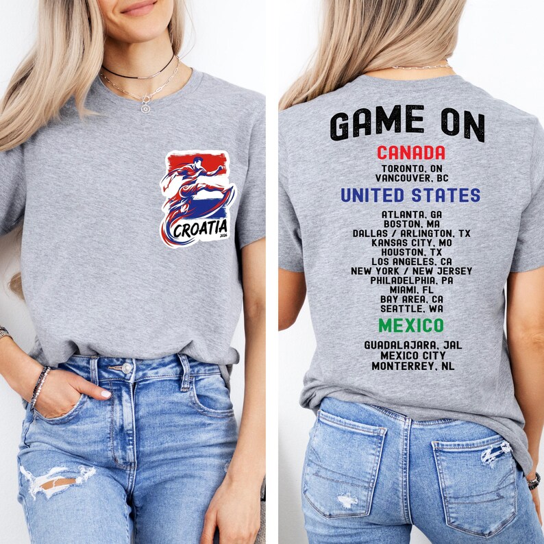 A woman wearing a grey t-shirt with a graphic of a person in a red and blue outfit, along with text that says "GAME ON CANADA" and a list of locations.