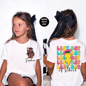 A young girl wearing a white t-shirt with a graphic design and text printed on it.