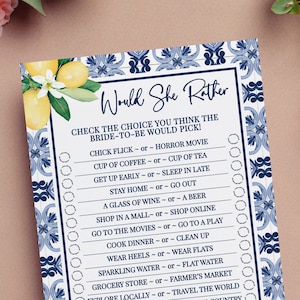 May include: A blue and white tiled background with a lemon and leaf design. The text "Would She Rather" is in a navy blue font. The game is a "Would She Rather" game for a bridal shower. The game asks questions about the bride-to-be's preferences.