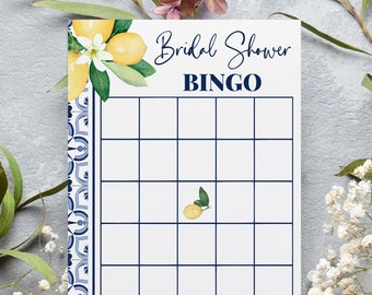 May include: A printable bridal shower bingo card with a lemon and floral design. The card has a blue and white tiled pattern border. The text "Bridal Shower Bingo" is at the top of the card. The instructions are at the bottom of the card: "Fill in each square with your guess of gift items that the bride-to-be will receive. Mark off the squares as gifts are opened. First to get 5 correct guesses in a row wins!"
