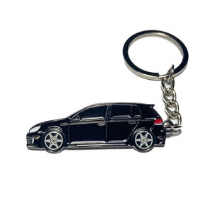 May include: Black metal keychain featuring a detailed silhouette of a Volkswagen Golf car. The keychain has a silver ring and chain.