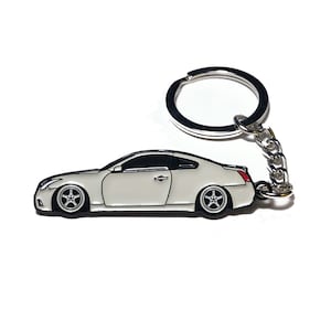 May include: White metal keychain featuring a detailed silhouette of a coupe car. The keychain has a silver ring and chain.