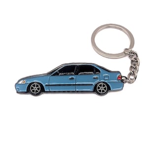 May include: A blue metal keychain shaped like a car. The keychain has a silver ring and chain.