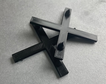 Puede incluir: Dos cruces de plástico negro con bordes redondeados y pequeños bultos en los extremos de cada brazo.