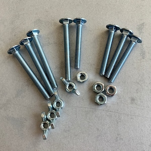 May include: A set of eight silver-toned metal screws with hexagonal heads and square nuts. The screws are arranged in two groups of four, with the nuts scattered around them.