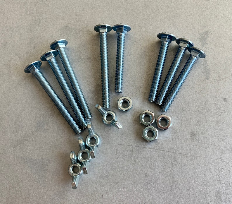 May include: A set of eight silver-toned metal screws with hexagonal heads and square nuts. The screws are arranged in two groups of four, with the nuts scattered around them.