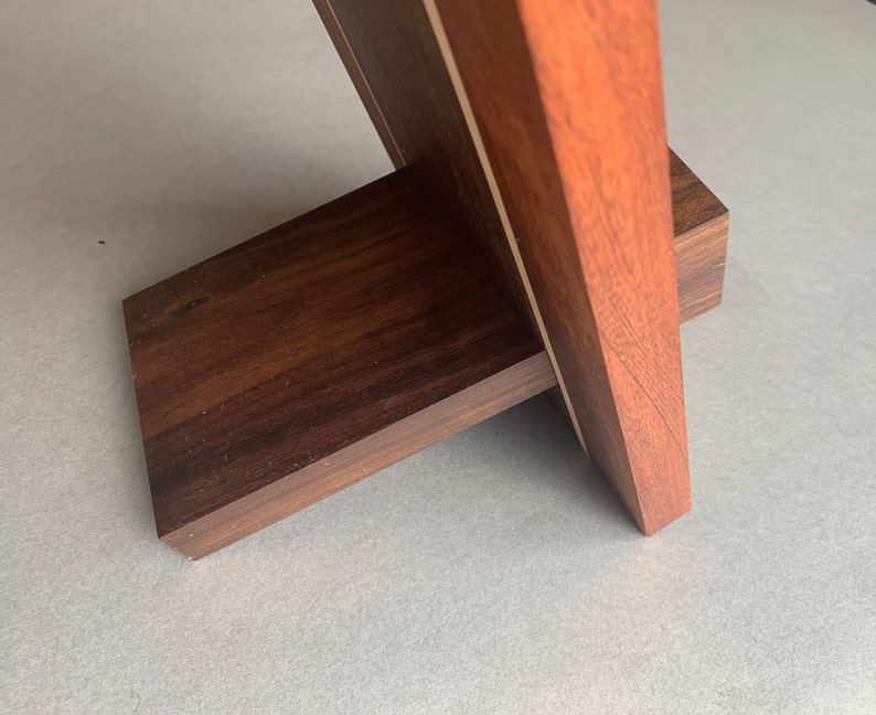 Puede incluir: Un marco de fotos de madera con un acabado marr&oacute;n oscuro y una incrustaci&oacute;n de madera clara. El marco tiene un soporte en la parte posterior para sostenerlo.