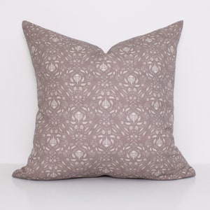 May include: A square throw pillow with a light brown background and a white floral pattern.
