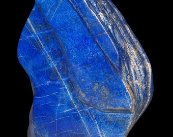 May include: A large, rough, blue lapis lazuli stone with white veins and a dark blue colour. The stone has a natural, irregular shape.