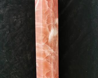 May include: A pink and white crystal point, also known as a wand or obelisk, with a smooth, polished surface. The crystal is a natural stone with a unique pattern of veins and inclusions.