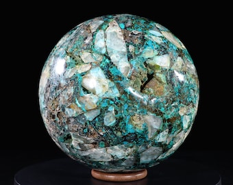 May include: A large, polished sphere of turquoise and quartz. The sphere is a deep blue-green colour with white and brown inclusions. It is displayed on a wooden base.
