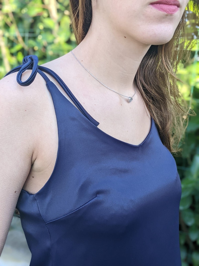 May include: A navy blue satin slip dress with thin straps that tie at the shoulders.