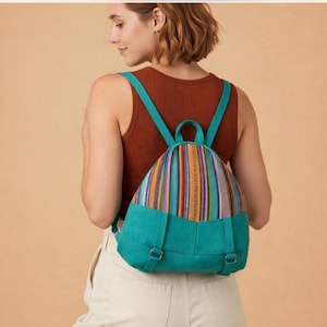 May include: A teal and multicolored striped backpack with teal straps and base. The backpack has a colorful striped pattern on the top portion and teal on the bottom. The straps are teal and adjustable. The backpack is worn on the back.