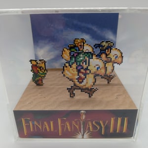 May include: A pixel art diorama featuring characters and creatures from Final Fantasy III. The scene includes a character on foot and a group riding a Chocobo. The base of the display case features the game's logo.