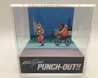 Op de afbeelding: Een 3D-diorama van het videospel Mike Tyson's Punch-Out!! met de personages Mike Tyson en een fietser op een stadsachtergrond.