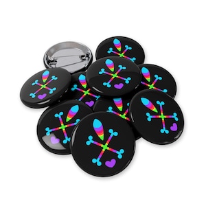 Może przedstawiać: Kolekcja czarnych, okrągłych guzików z kolorowym wzorem. Każdy guzik ma tęczowy wzór z incydentu i sercem. Jeden guzik ma srebrny tył szpilki.