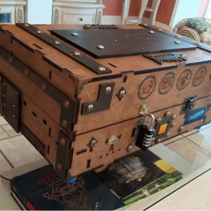 Puede incluir: Un cofre del tesoro de madera con detalles met&aacute;licos y una cerradura de combinaci&oacute;n. El cofre tiene un tinte marr&oacute;n y una tapa de cuero marr&oacute;n oscuro. Hay varios s&iacute;mbolos tallados en la parte delantera del cofre.