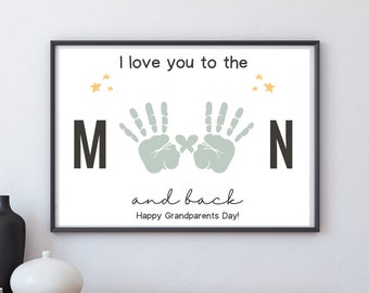 May include: A white printable art print with black text that reads "I love you to the moon and back. Happy Grandparents Day!" with two green handprints in the centre of the print. There are also four small yellow stars on the print.