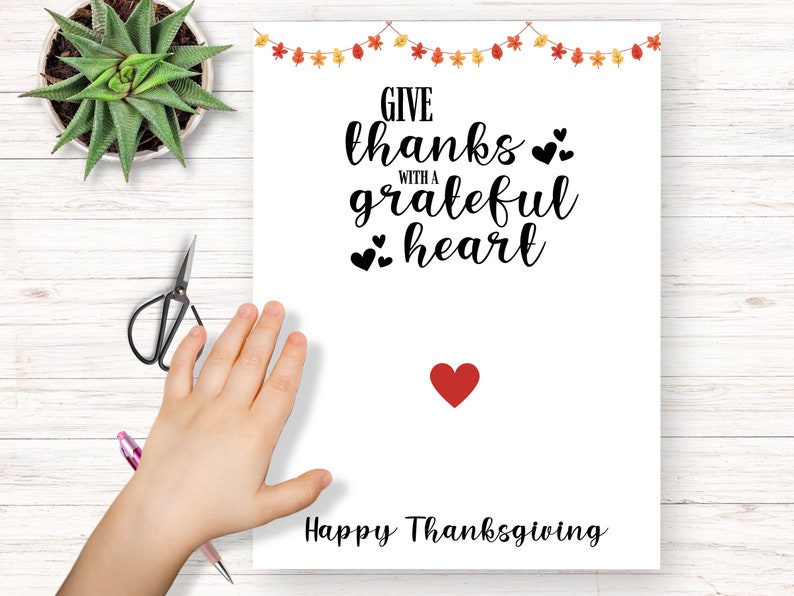 K&ouml;nnte beinhalten: Eine wei&szlig;e, druckbare Karte mit dem Text "Give thanks with a grateful heart" und einem roten Herzen unten. Der Text "Happy Thanksgiving" befindet sich am unteren Rand der Karte.