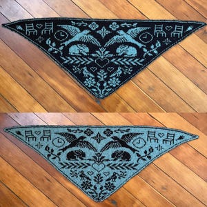 May include: Triangular knitted shawl in black and teal. The shawl features a repeating pattern of birds, chairs, clocks, and floral elements. The design is symmetrical, with a heart shape at the centre.