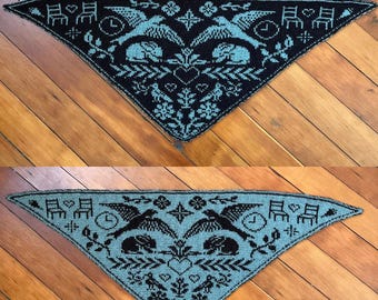 May include: Triangular knitted shawl in black and teal. The shawl features a repeating pattern of birds, chairs, clocks, and floral elements. The design is symmetrical, with the central motif being a heart shape.