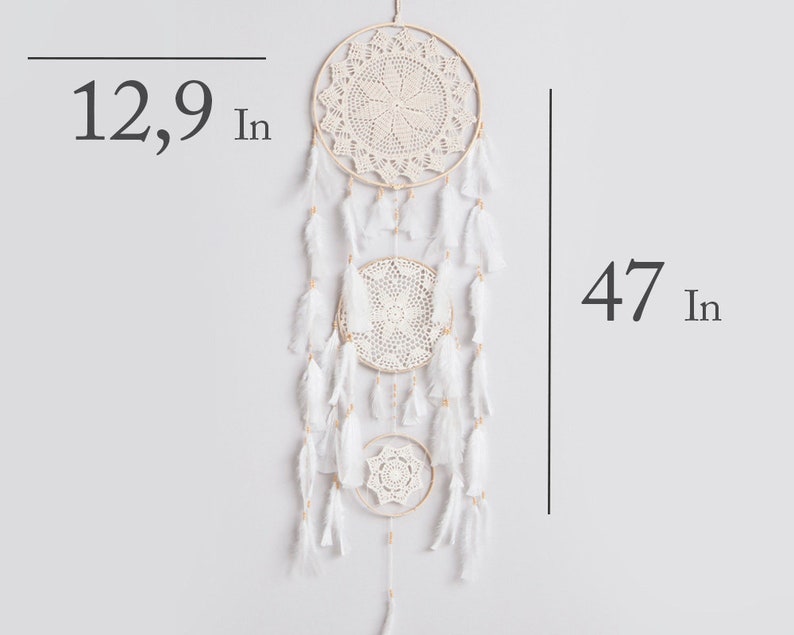 May include: White dream catcher with three circular crocheted hoops and white feathers hanging from the bottom. The dream catcher is 47 inches long and the largest hoop is 12.9 inches in diameter.